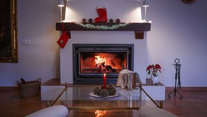 Una chimenea con fuego encendido, un faldón con un calcetín rojo y una mesa de vidrio al frente.