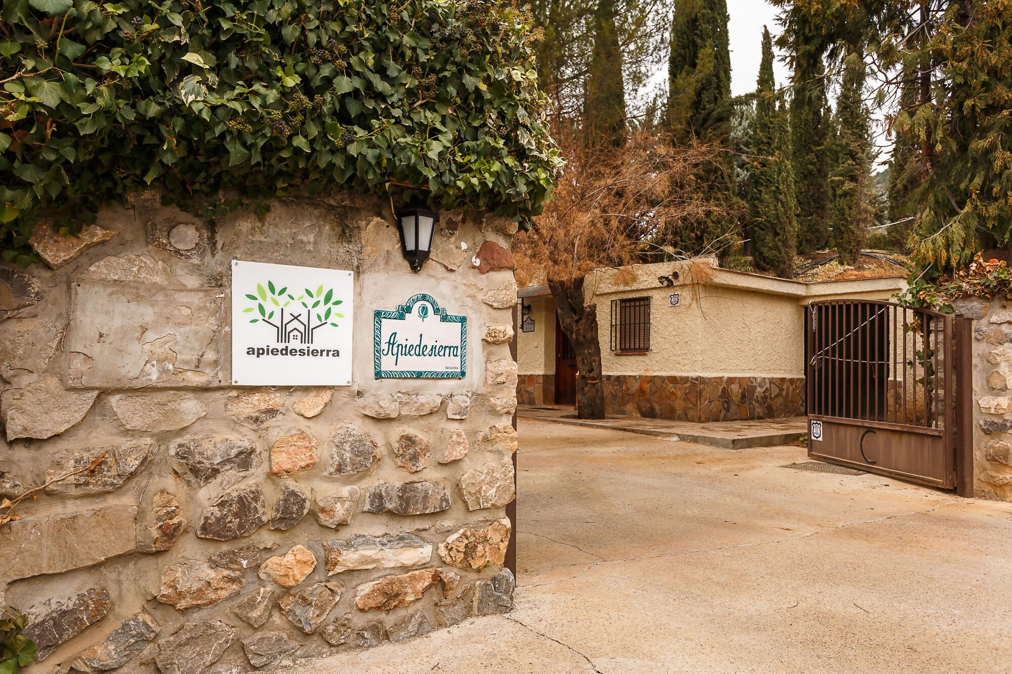 A stone wall with signs for 'Apiedesierra' and 'Apiedesierra Hotel'.