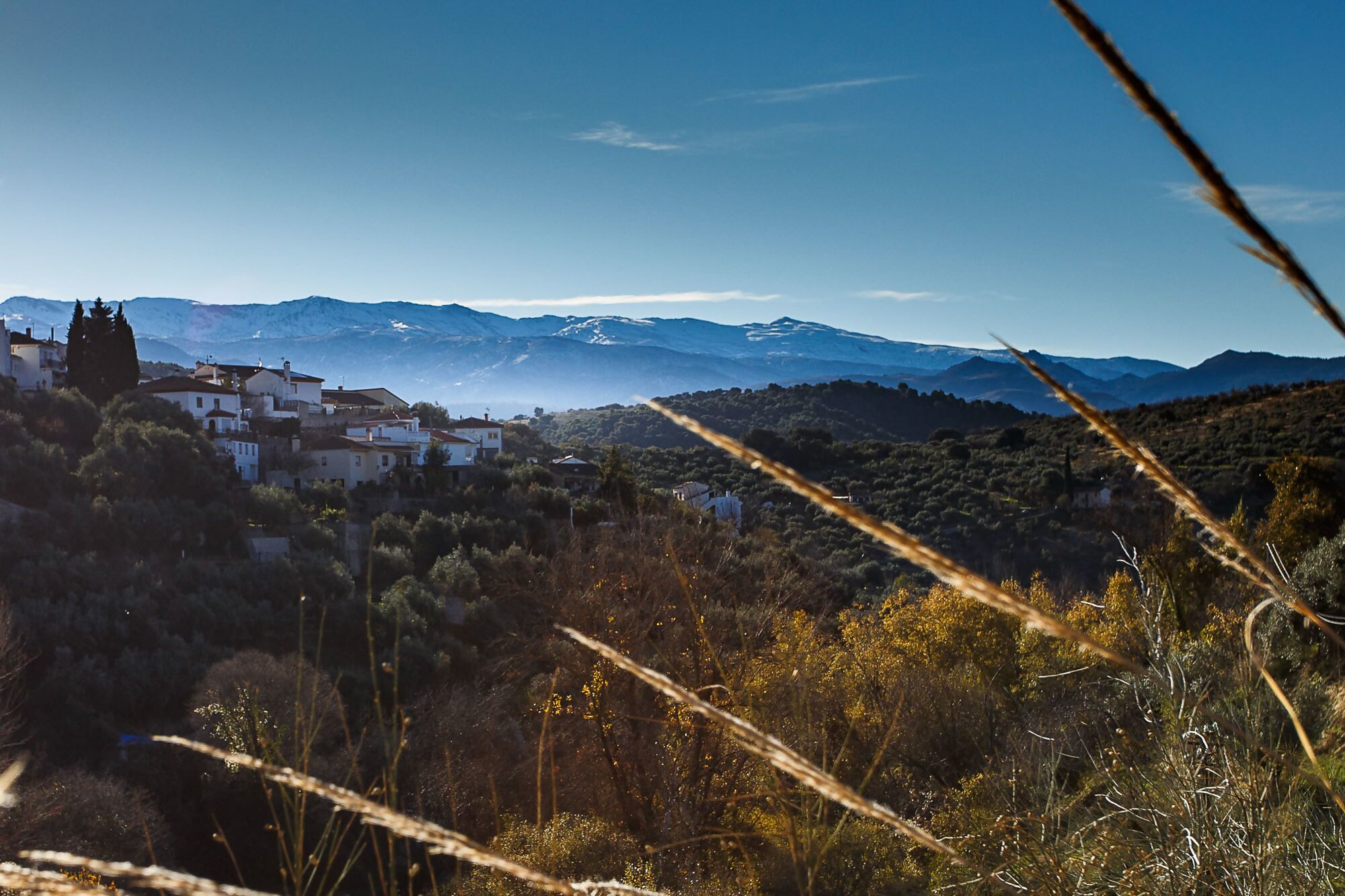 Paisaje montañoso con un pueblo de edificios blancos y cielo despejado.
