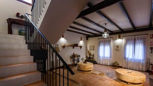 A staircase leading to a living area with a stone table, a chandelier, and a view of the outside through a window. - San Acacio Mill - Casa Rural Darro (Huetor De Santillan)