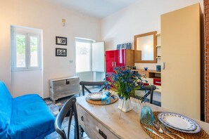 A room with a bed, a table with plates and a vase, a red cabinet, and a mirror.