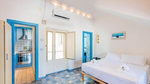 Ein Schlafzimmer mit einem Bett, ein Badezimmer mit Dusche und eine Küchenzeile.