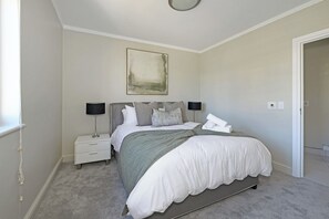 Quarto com cama, mesas de cabeceira, abajur e um quadro na parede.