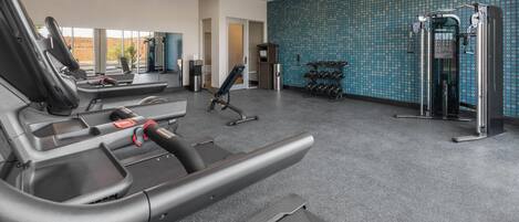 A gym with treadmills, a weight machine, and dumbbells.