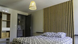 Une chambre à coucher comprenant un lit, une armoire, un miroir et un luminaire suspendu.