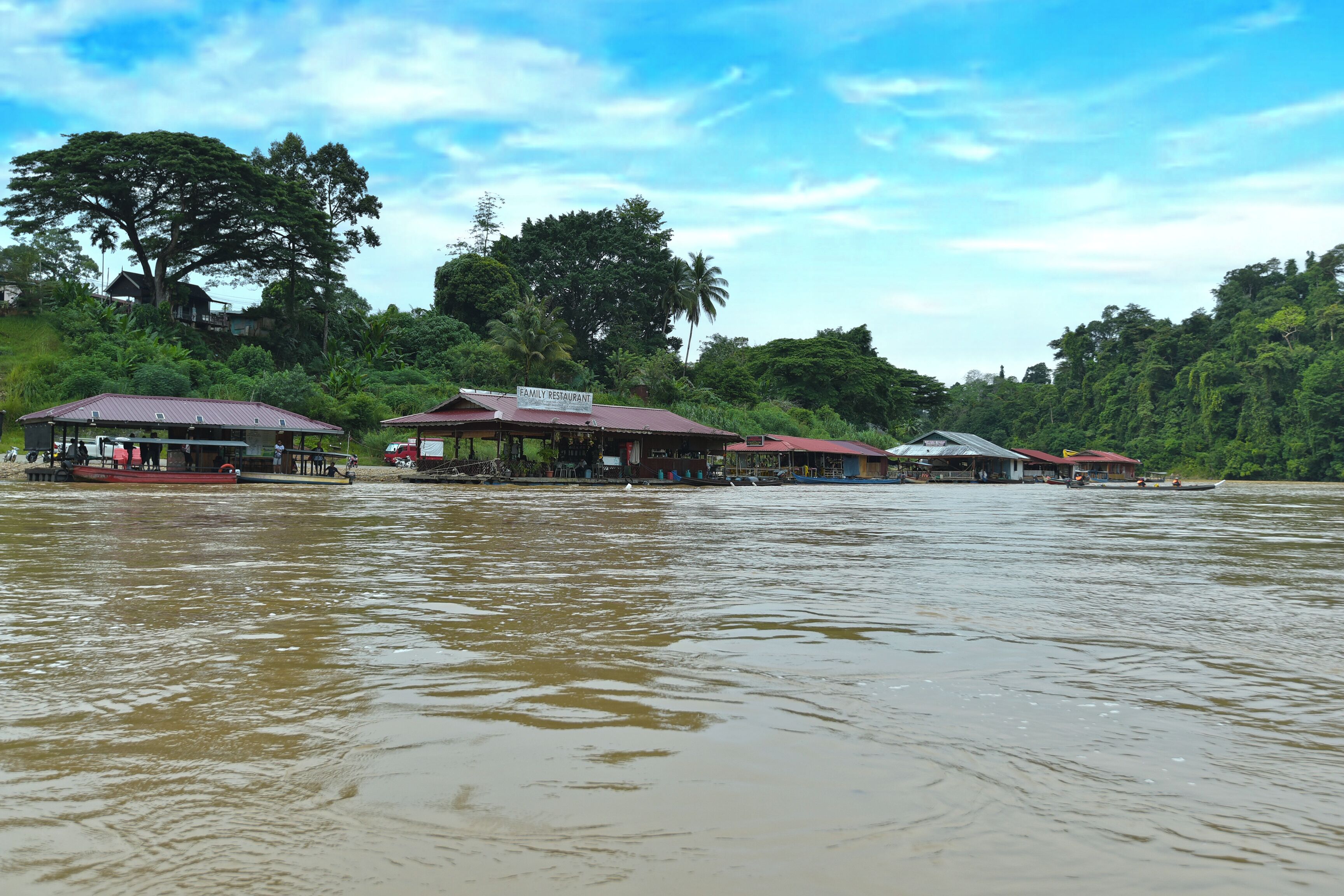 A riverside restaurant with multiple buildings, including a prominent 'Family Restaurant' sign.