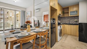 A modern kitchen with wooden cabinets, a built-in oven, and a washing machine. - Sedana by Kozystay - Paskal (Bandung)