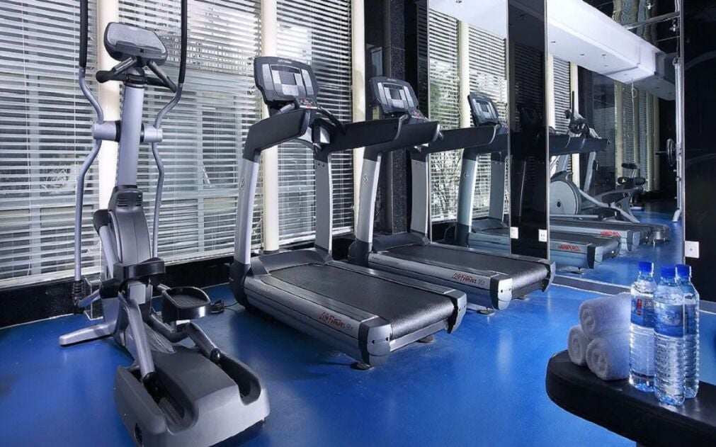 Een fitnessruimte met loopbanden, een hometrainer en een spiegel.