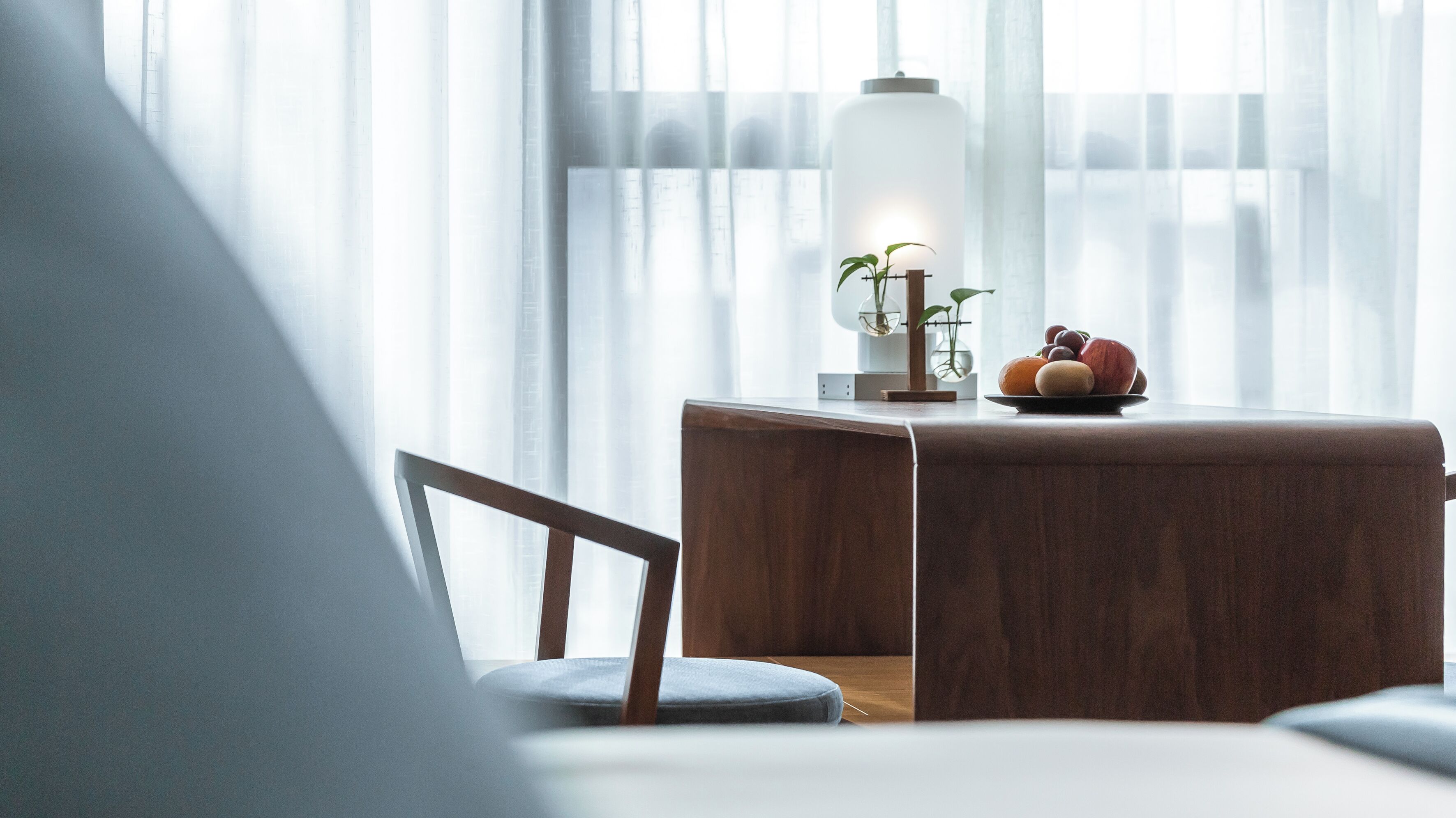 A modern room with a wooden side table, a lamp, and a fruit bowl.