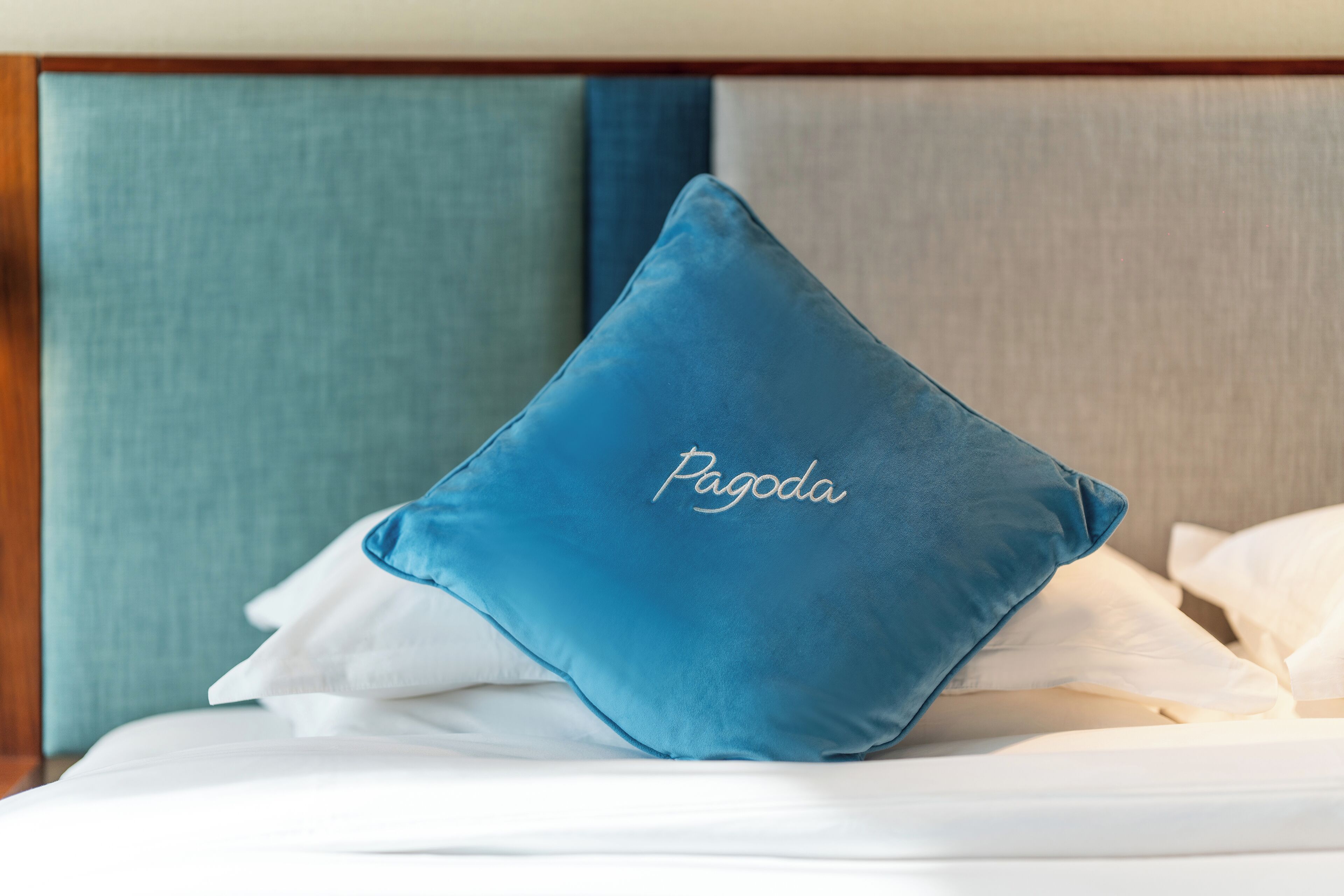 A bed with a blue pillow labeled "Pagoda" and white bedding.