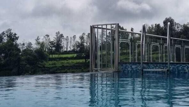 A swimming pool with clear water and a metal structure in the background. - Shreejee Villa (Mahabaleshwar)