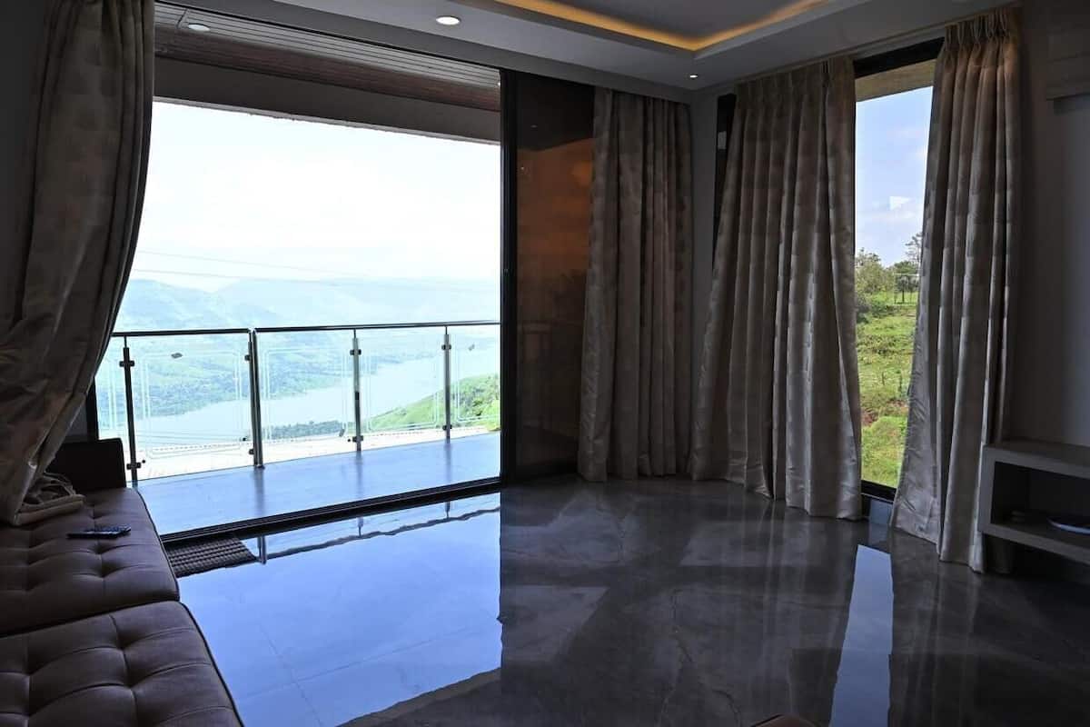 A spacious room with a large window offering a view of a lake and mountains.