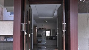 A set of stone steps leading to a modern entrance with wooden doors and a recessed ceiling light. - Shreejee Villa (Mahabaleshwar)