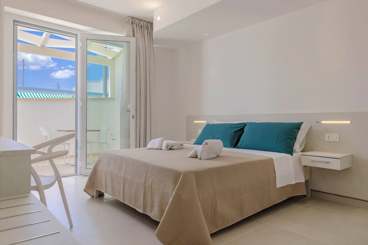 A hotel room with a bed, a desk, and a chair.