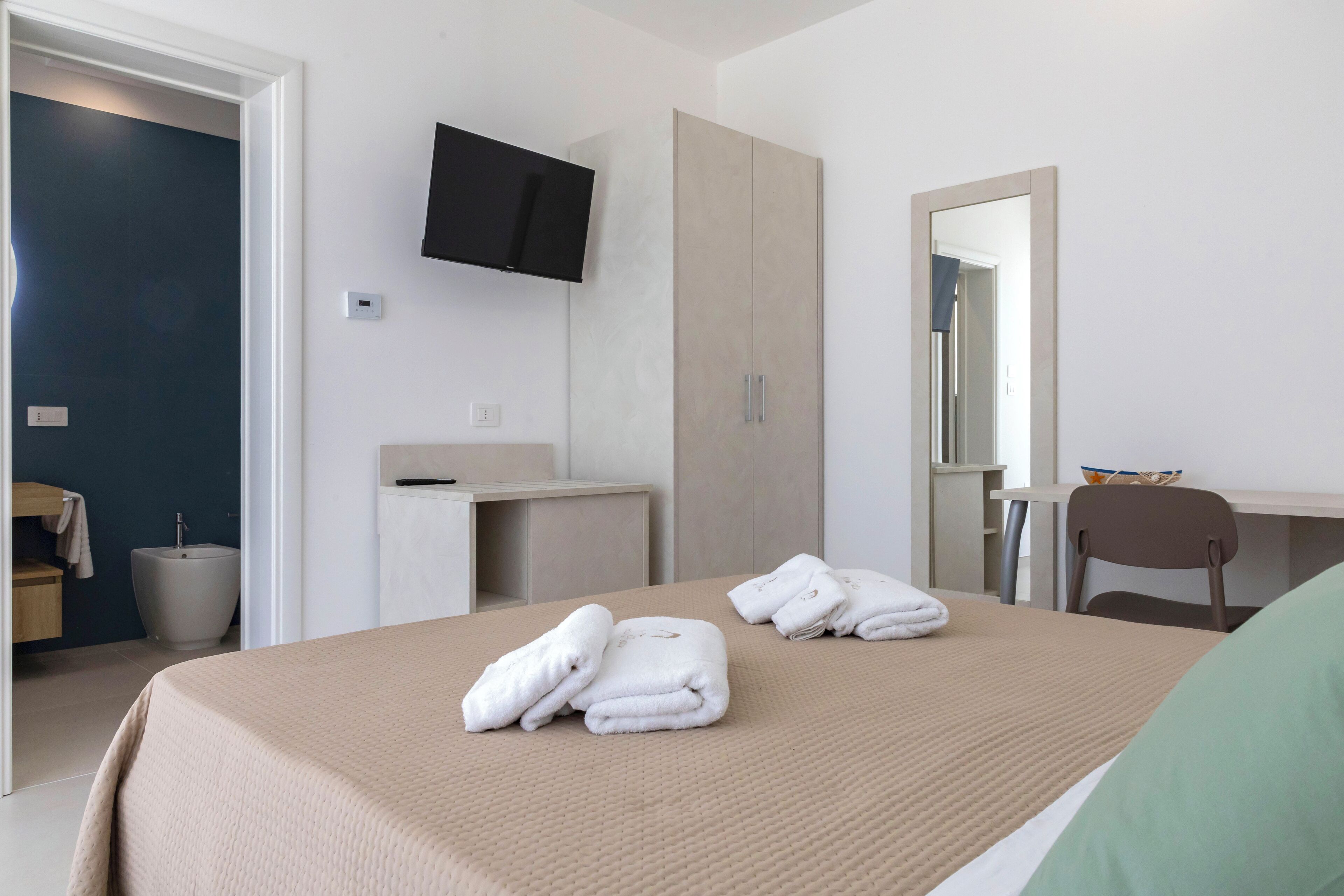 Une chambre d’hôtel comprenant un lit, un bureau, une chaise, une télévision et une salle de bain.