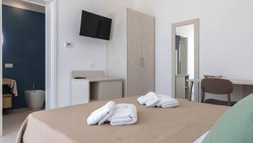 Une chambre d’hôtel comprenant un lit, un bureau, une chaise, une télévision et une salle de bain.