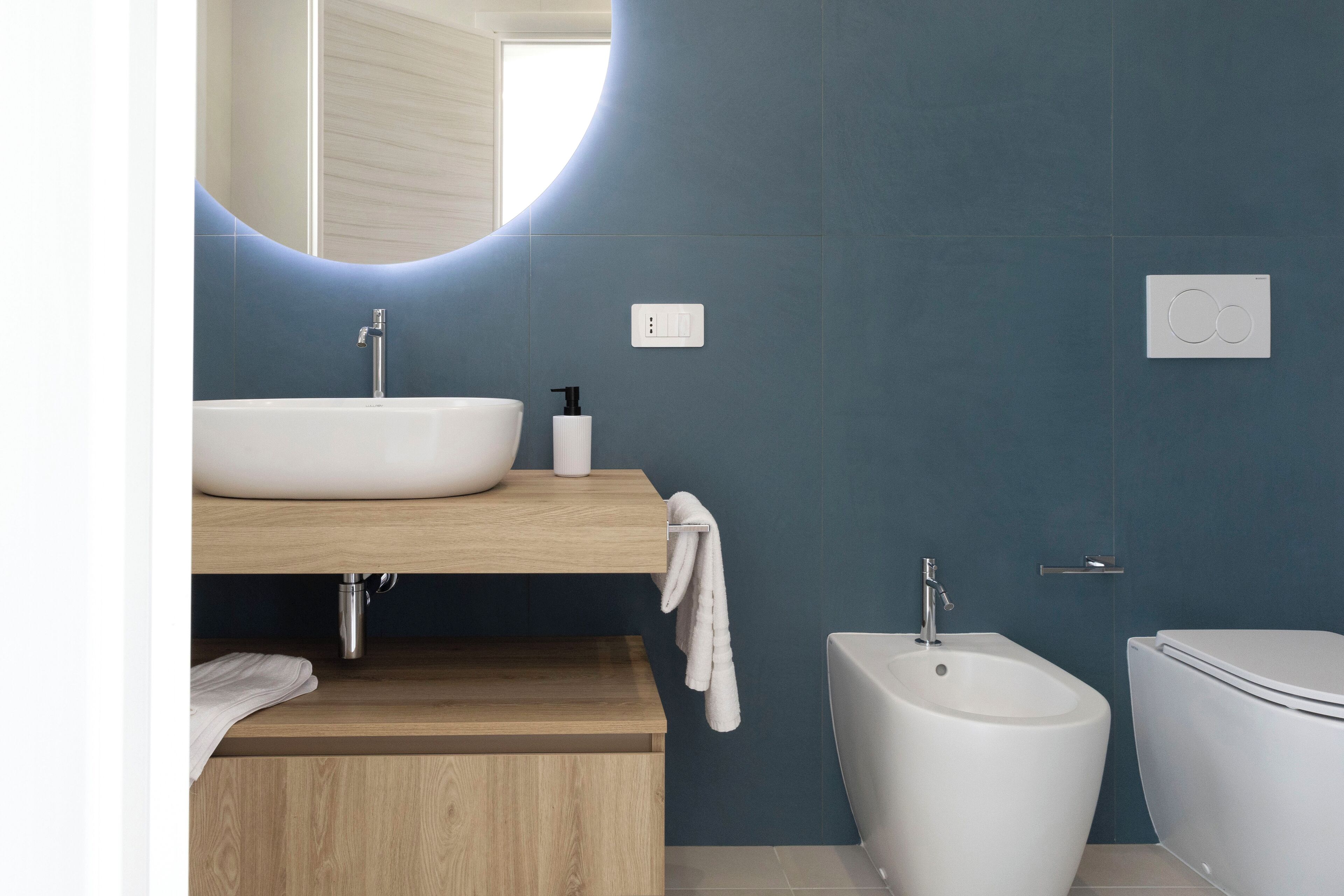 A modern bathroom with a freestanding sink, a bidet, and a toilet.