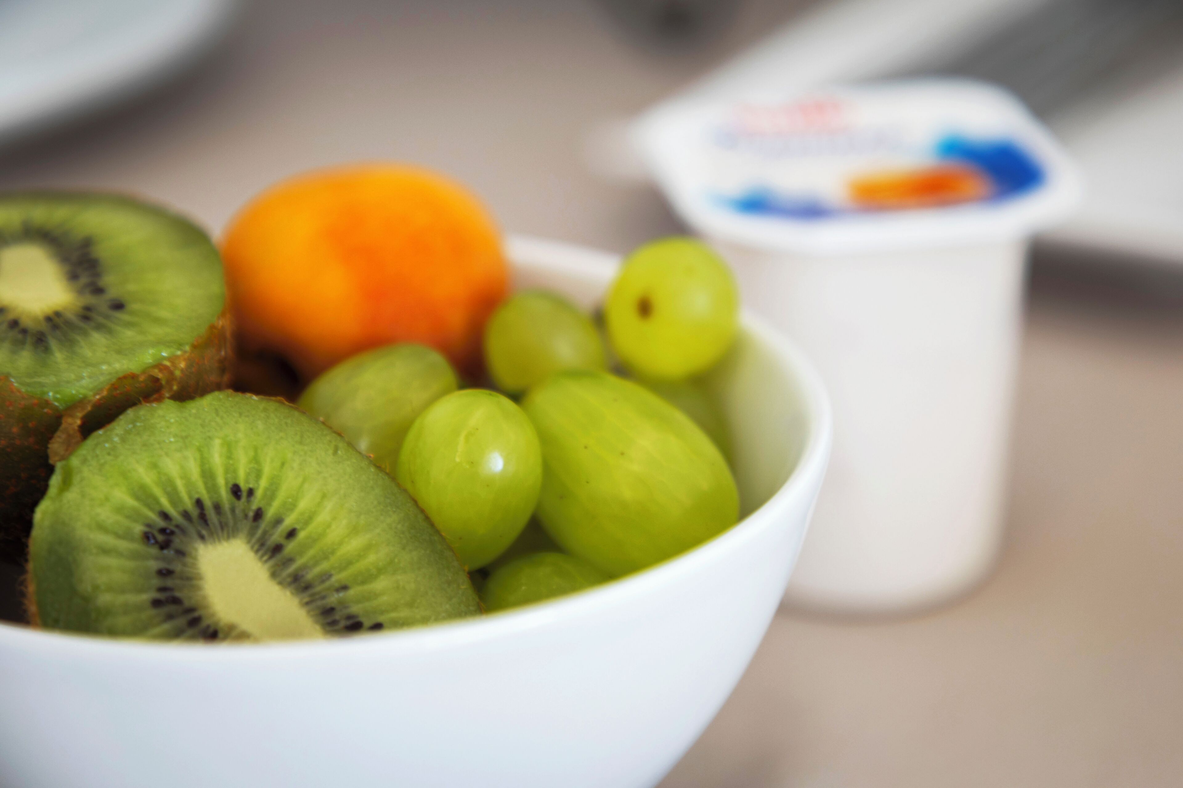Un bol contenant des tranches de kiwi et des raisins verts.