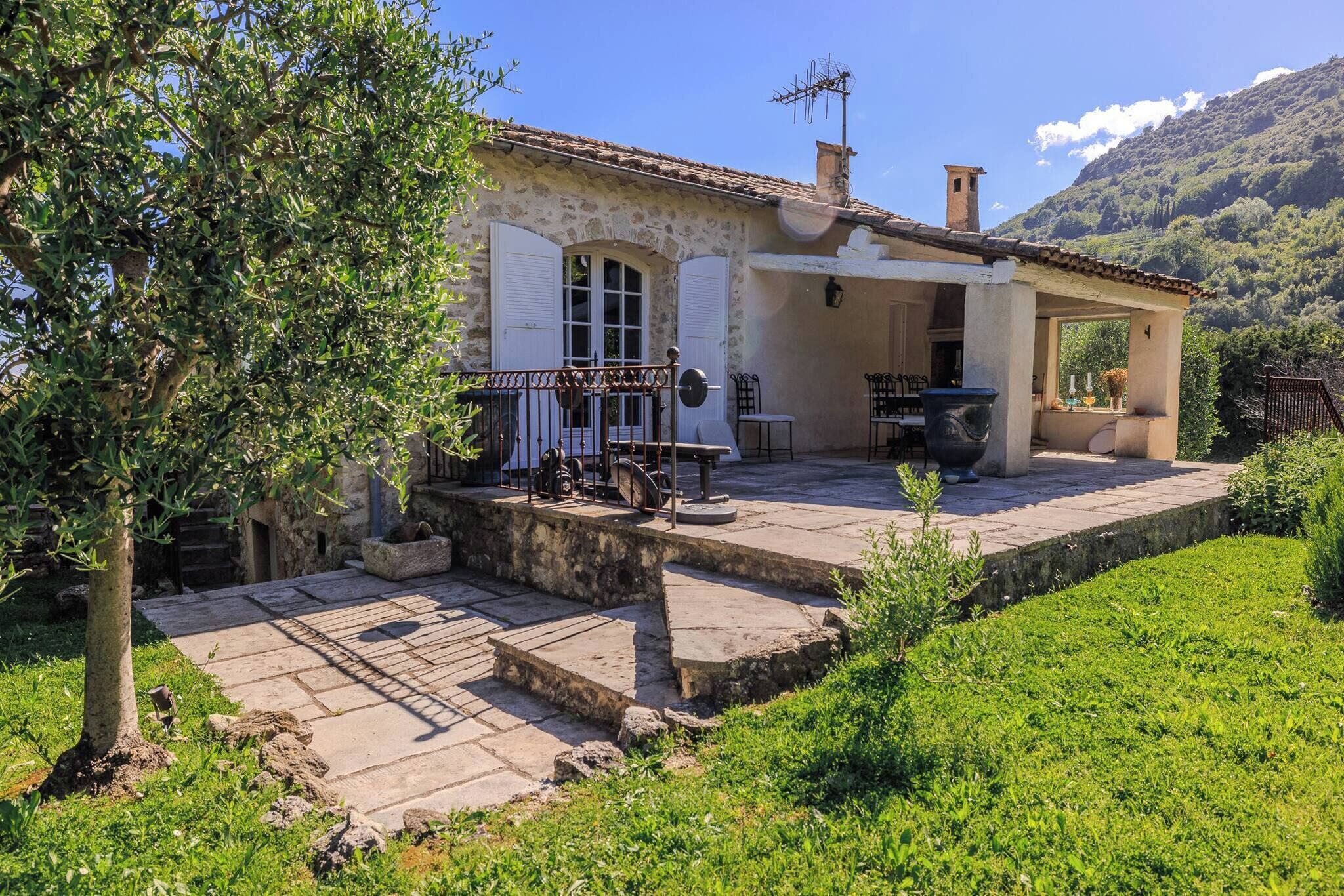 A stone building with a patio, outdoor seating, and a mountain backdrop.