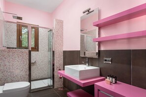A modern bathroom with a glass shower enclosure, a white sink, and pink countertops. - Calm Retreat Villa Lagonisi (Saronikos)
