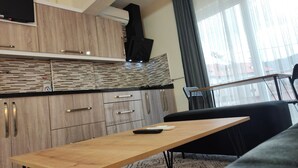 Una cucina moderna con mobili in legno, un piano di lavoro nero e un piano cottura integrato. C'è un tavolo da pranzo con un telecomando sopra.