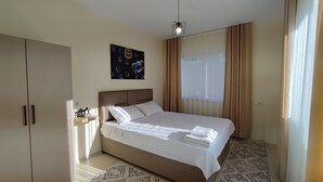 Camera d'albergo con un letto, un armadio, un'opera d'arte a parete e una finestra con tende.