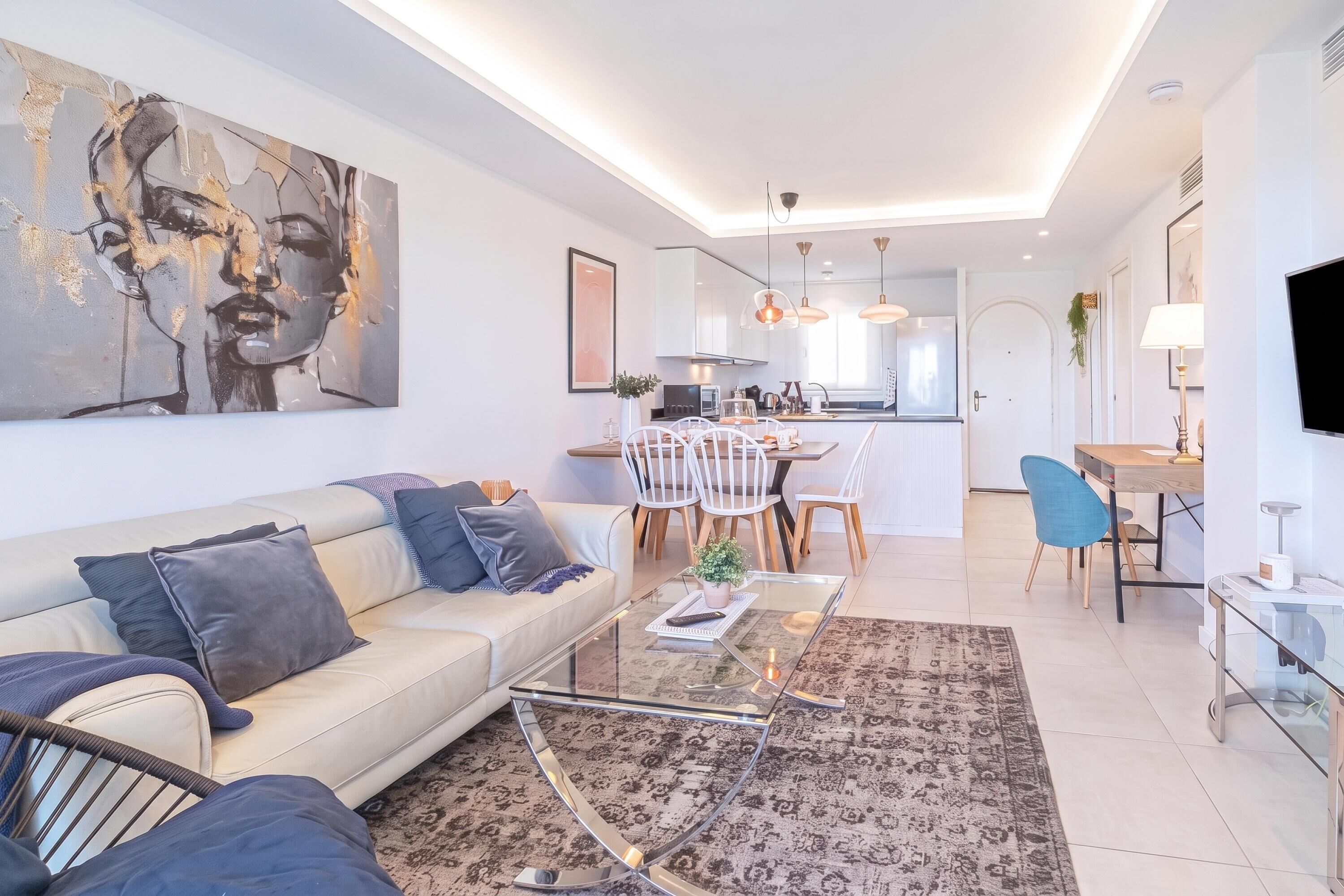 A modern living room with a sofa, coffee table, and a large abstract painting.