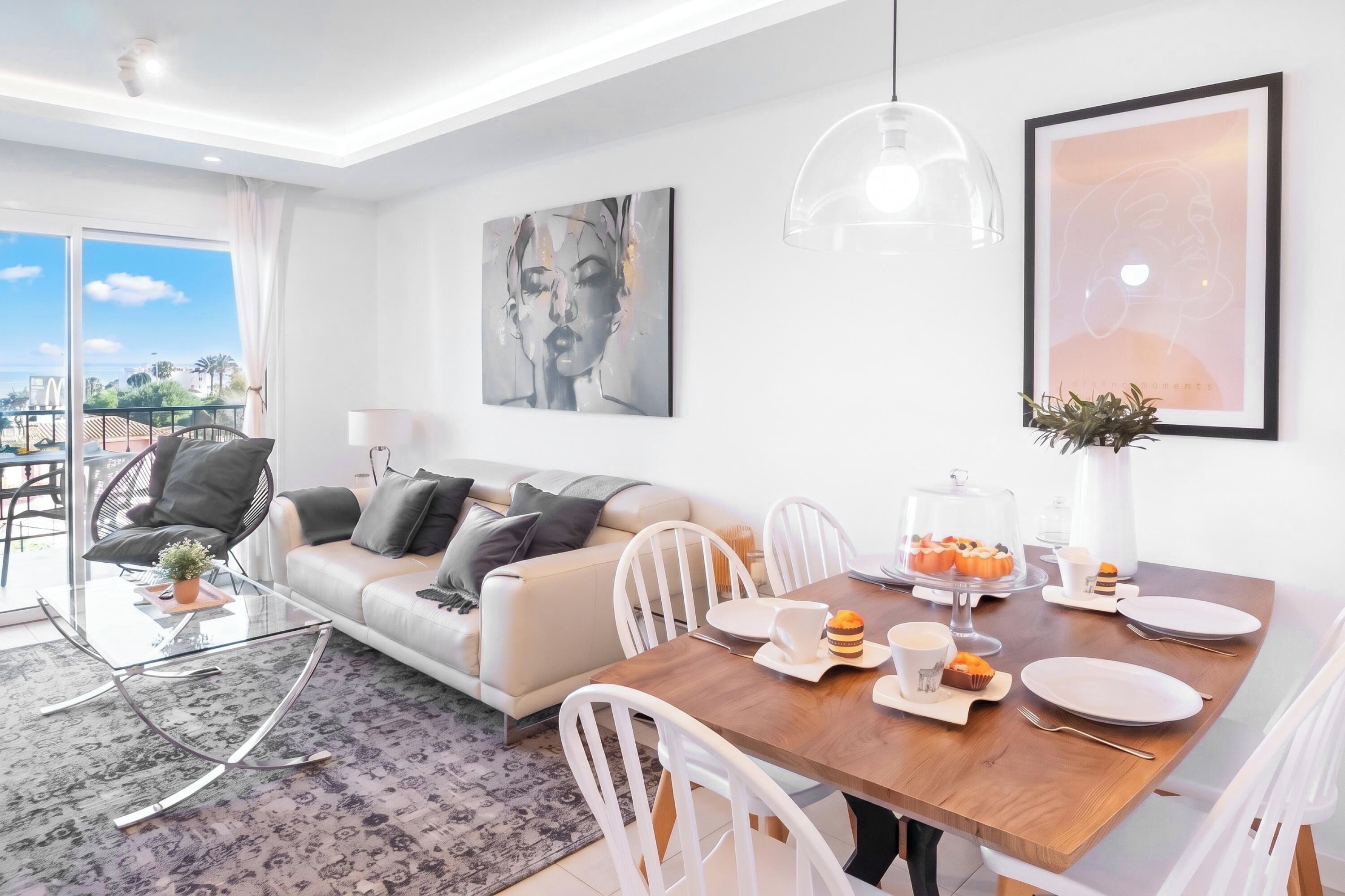 A modern living room with a sofa, dining table, chairs, and artwork.