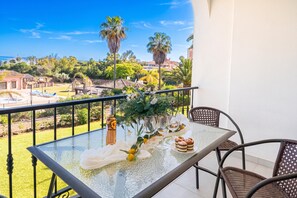 A balcony with a glass table, chairs, and a bottle of wine. - Luxury Family Riviera Del Mar (Mijas)
