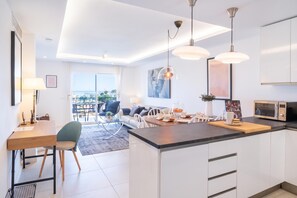 A modern kitchen with a central island, dining area with chairs, and a view to the outside. - Luxury Family Riviera Del Mar (Mijas)