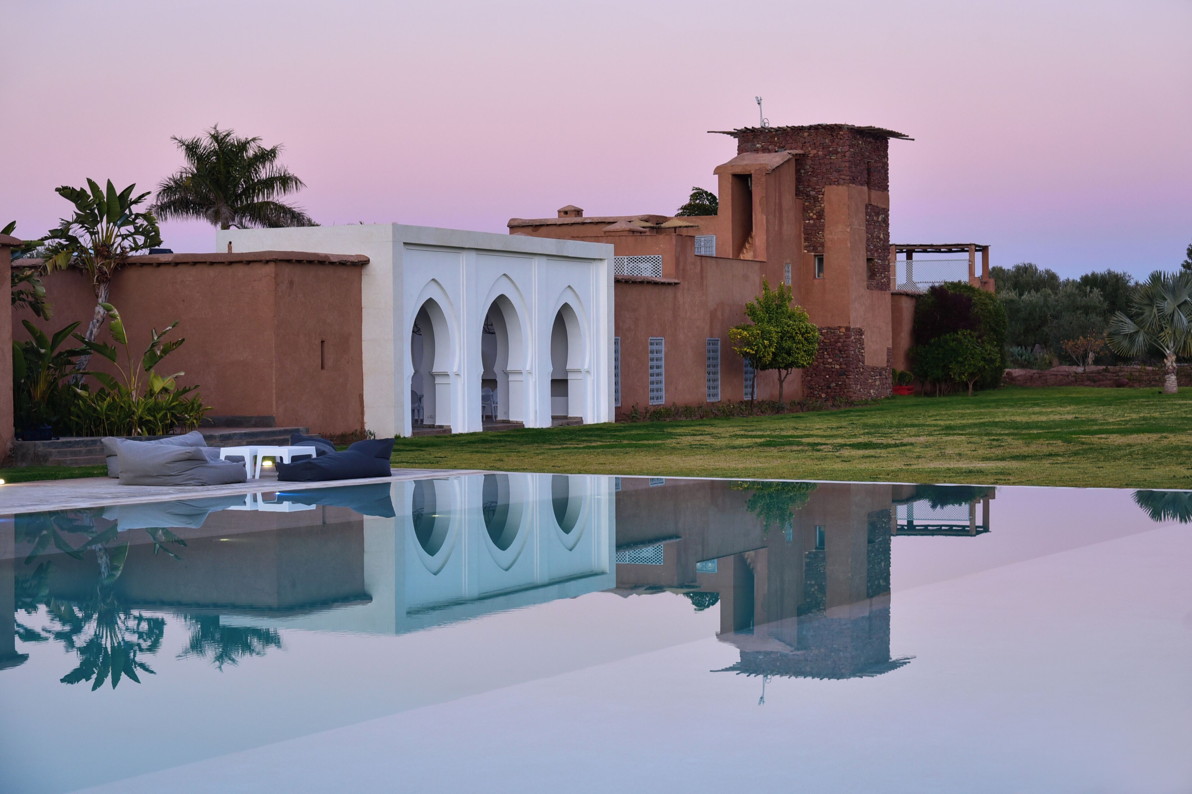 A modern building with a pool, arched windows, and a tower.