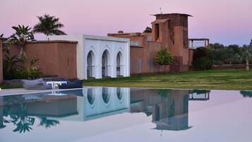Un edificio moderno con piscina, ventanas arqueadas y una torre.