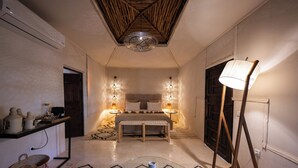 A bedroom with a bed, bedside lamps, a bedside table, a floor lamp, a wall-mounted shelf, and a patterned rug. - Domaine Darsyada Boutique Hôtel – Boutique Hôtel Deluxe & Spa (Sidi Abdallah Ghiat)