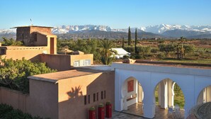 A traditional building with a courtyard, a view of snow-capped mountains, and a palm tree. - Domaine Darsyada Boutique Hôtel – Boutique Hôtel Deluxe & Spa (Sidi Abdallah Ghiat)
