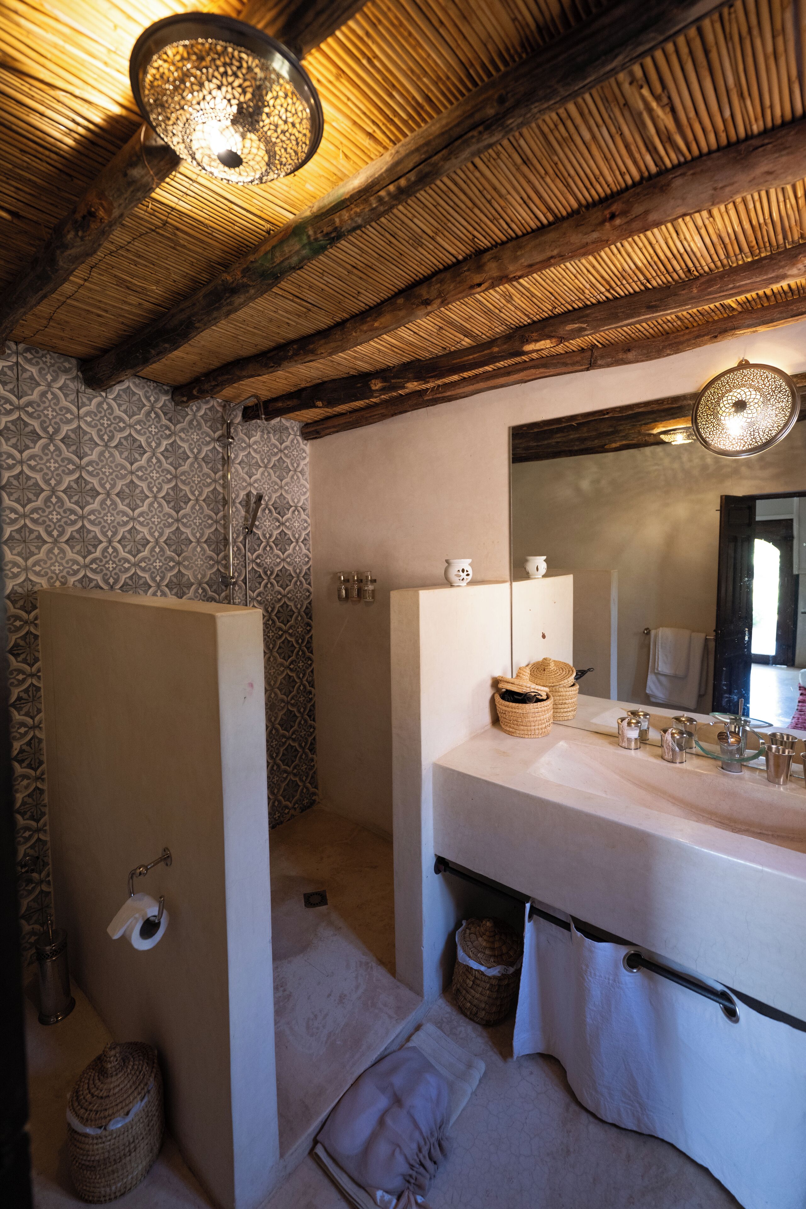 A bathroom with a wooden ceiling, a large mirror, a sink, and a shower.