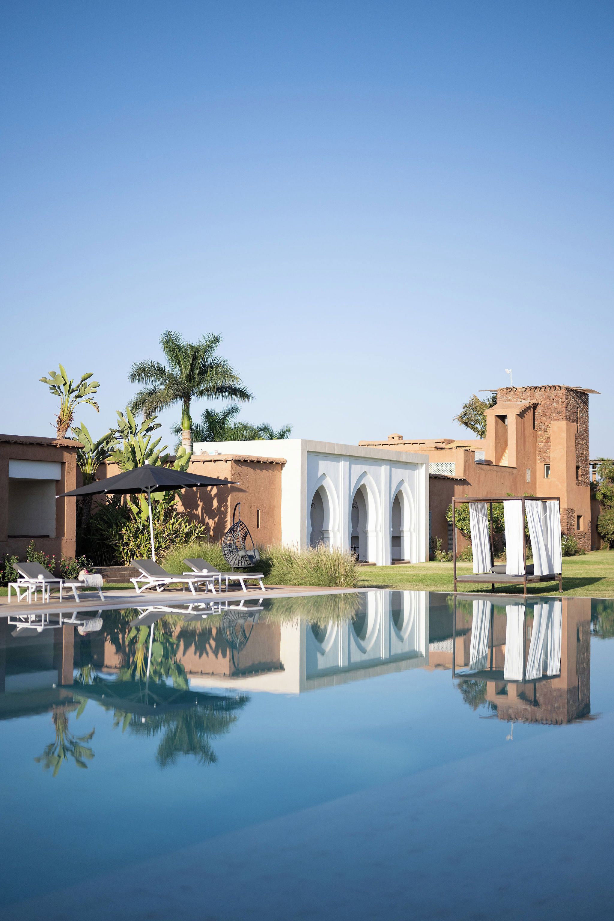 Un resort con piscina, sillas de descanso y un edificio con arcos.