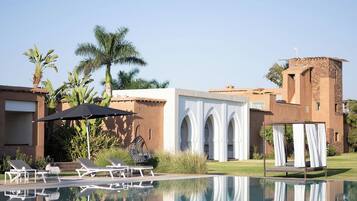Un resort con piscina, sillas de descanso y un edificio con arcos.