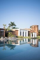 A resort with a swimming pool, lounge chairs, and a building with arches.
