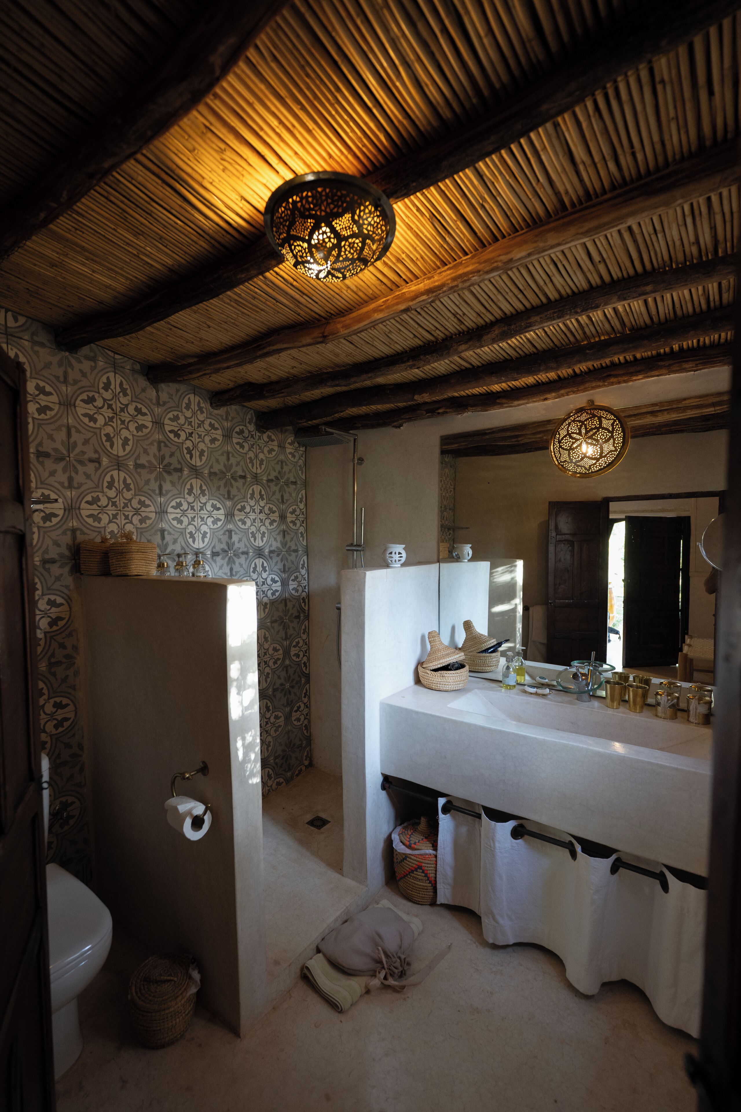A bathroom with a rustic ceiling, a large mirror, and a sink with towels.