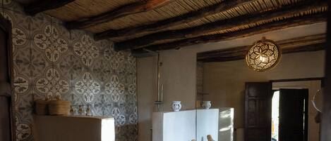 A bathroom with a rustic ceiling, a large mirror, and a sink with towels.