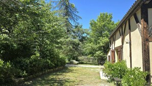 A rural property with a gravel path leading to a building with a traditional half-timbered facade. - Charming Cottage with Pool and Private Parking in Périgord Noir (Berbiguières)