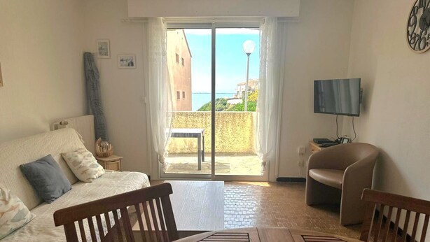 A bedroom with a bed, a wooden table, a chair, a TV, and a balcony with a view of the sea. - T3 Apartment 6 ppl, terrace and parking 30m from beach (Collioure)