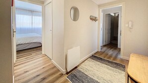 A room with a bed, a radiator, a mirror, and a door leading to another room. - Ideal Beach T2 Cabin with Parking, Pets Allowed (Cucq-Stella Plage)