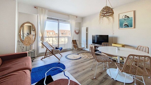 A modern living room with a sofa, chairs, a dining table, a TV, and a large window with curtains. - Ideal Beach T2 Cabin with Parking, Pets Allowed (Cucq-Stella Plage)