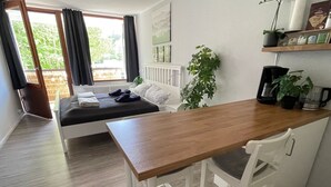 A bedroom with a bed, a bedside table, a chair, a window with curtains, and a view of the outdoors. - Vacation apartment in Freudenstadt-Kniebis I, Black Forest (Freudenstadt)
