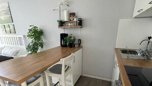 A small kitchenette with a wooden countertop, white chairs, a coffee machine, a potted plant, and a shelf with kitchen items. - Vacation apartment in Freudenstadt-Kniebis I, Black Forest (Freudenstadt)