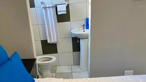Un dormitorio con una cama, un inodoro blanco y un lavabo en el baño.