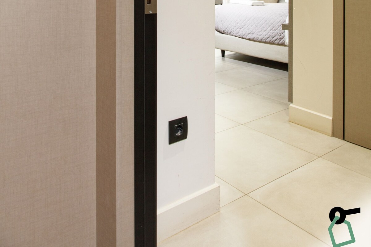 A hotel room with a bed, a bathroom with a toilet, a shower, and a door with a number indicating the room.