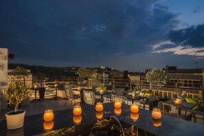 A rooftop terrace with outdoor seating, potted plants, and candles. - Hotiday Athens Acropolis (Athens)