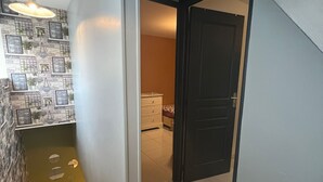 A staircase leading to a bedroom with a bed and dresser, a dark door, and a wall with framed pictures and plants. - 20 MIN PARIS/ 10 MIN ORLY AIRPORT CASA PARADIS VERT (Villeneuve-le-Roi)